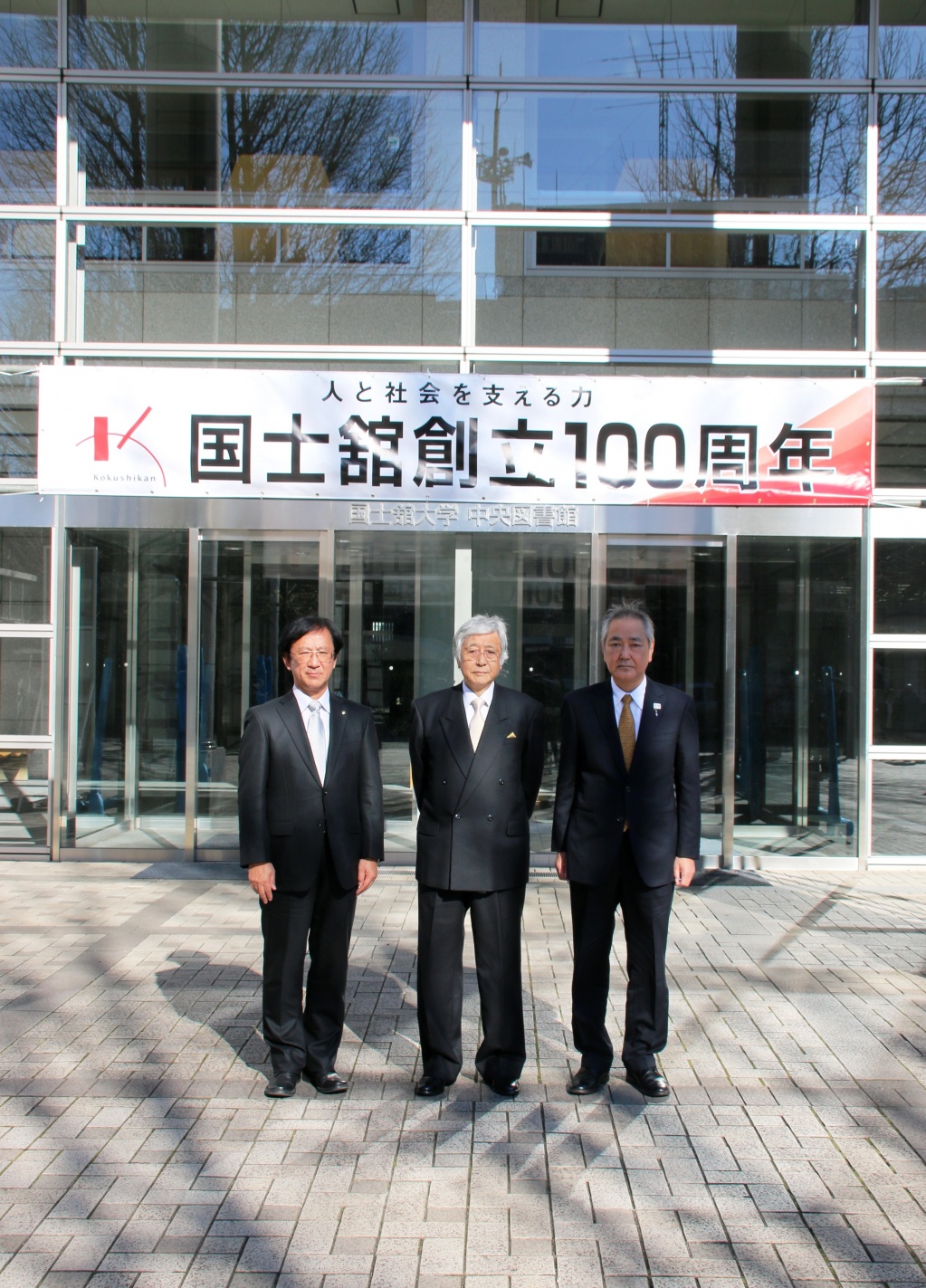 中央図書館入口に掲げられた創立100周年を祝う横断幕の前で。
左から佐藤学長、大澤理事長、福田校長
