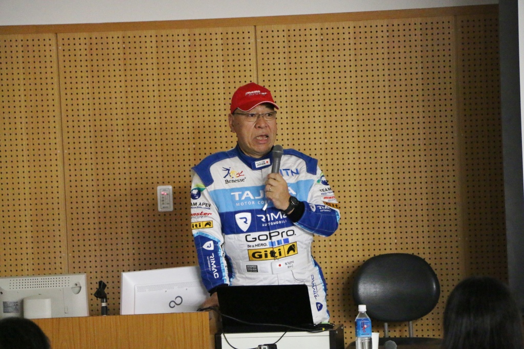 レーシングスーツを着て講演する田嶋氏