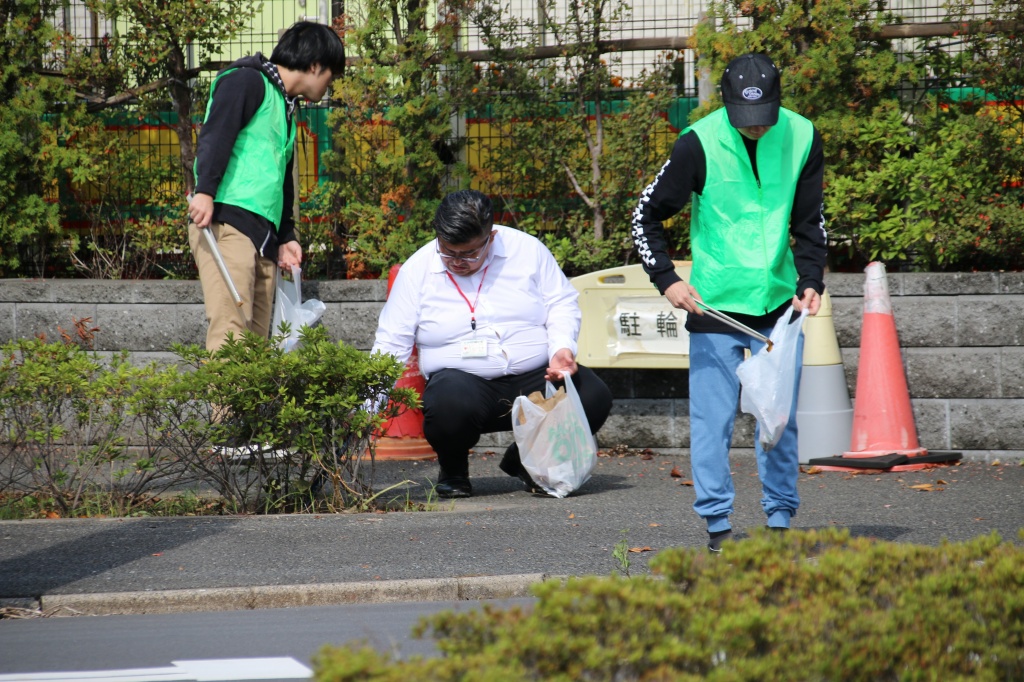 大学近隣の道路でゴミを拾う学生と教職員