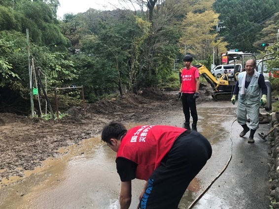 南浅川地域集落の道路に堆積した泥を掻き出し洗浄している学生ボランティア