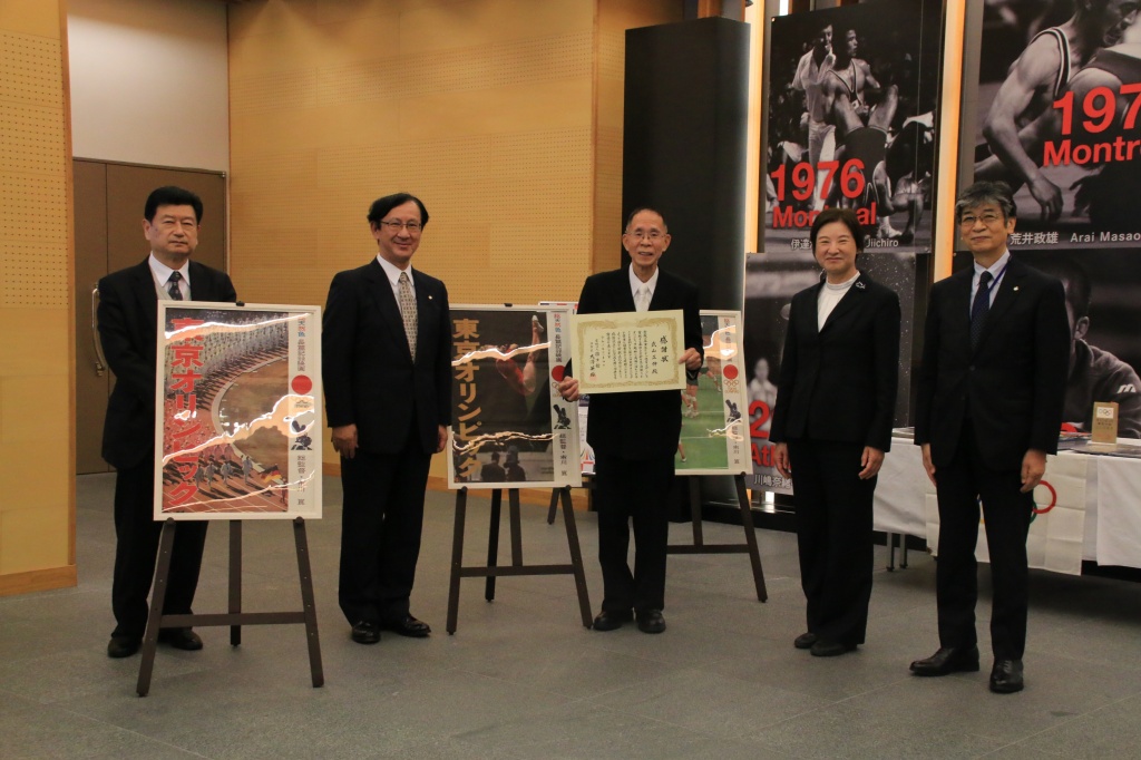 臨時展示の前で記念撮影。左から、村岡学部長、佐藤学長、武山さん、田原教授、入澤室長