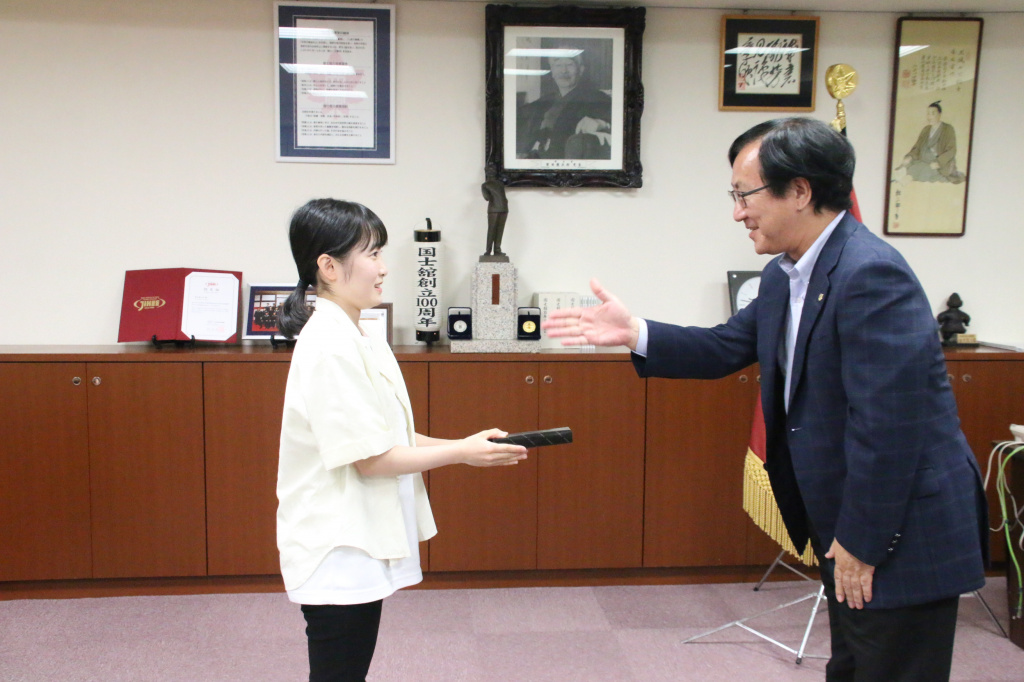 佐藤学長から記念品を受け取る中村さん