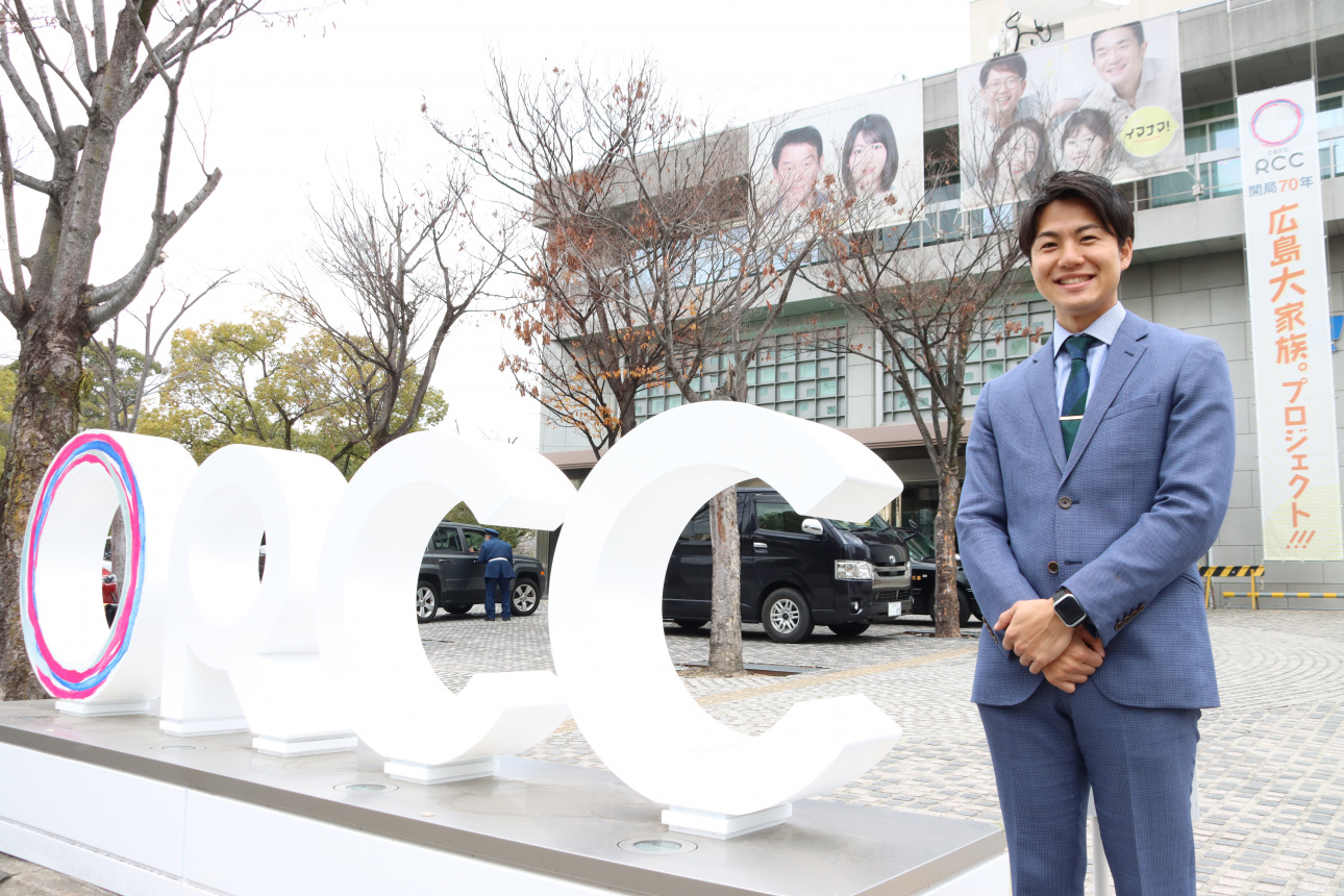 放送局社屋の前で笑顔を見せる伊東さん