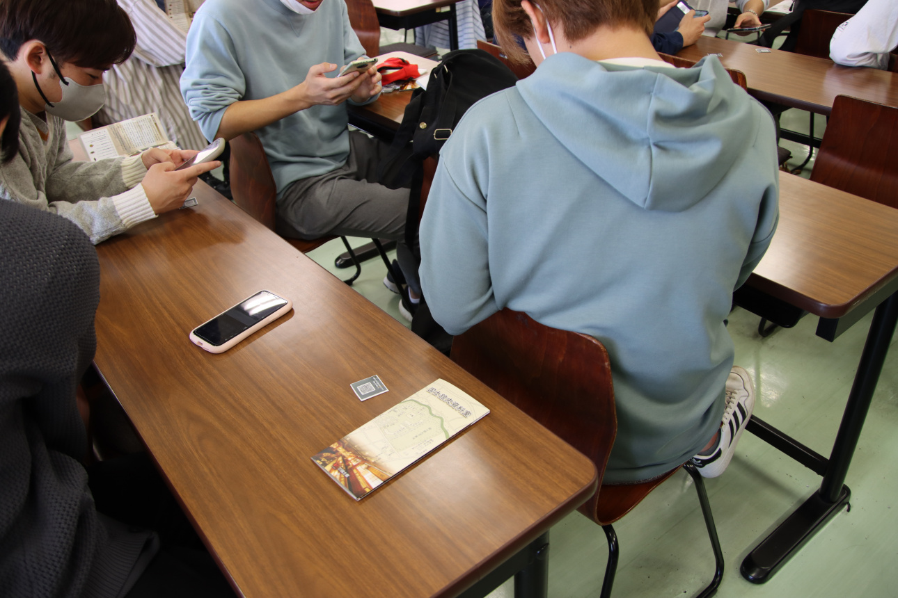 スマートフォンを使いQRコードを読み込んでクイズに挑戦する学生ら