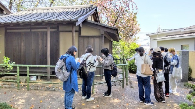 松陰神社境内の松下村塾の再現建築を見学する学生ら