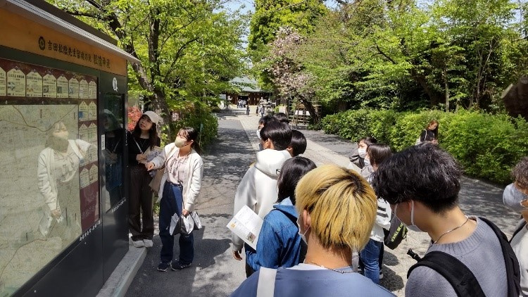 松陰神社で4年生の解説を聴く1年生の学生ら