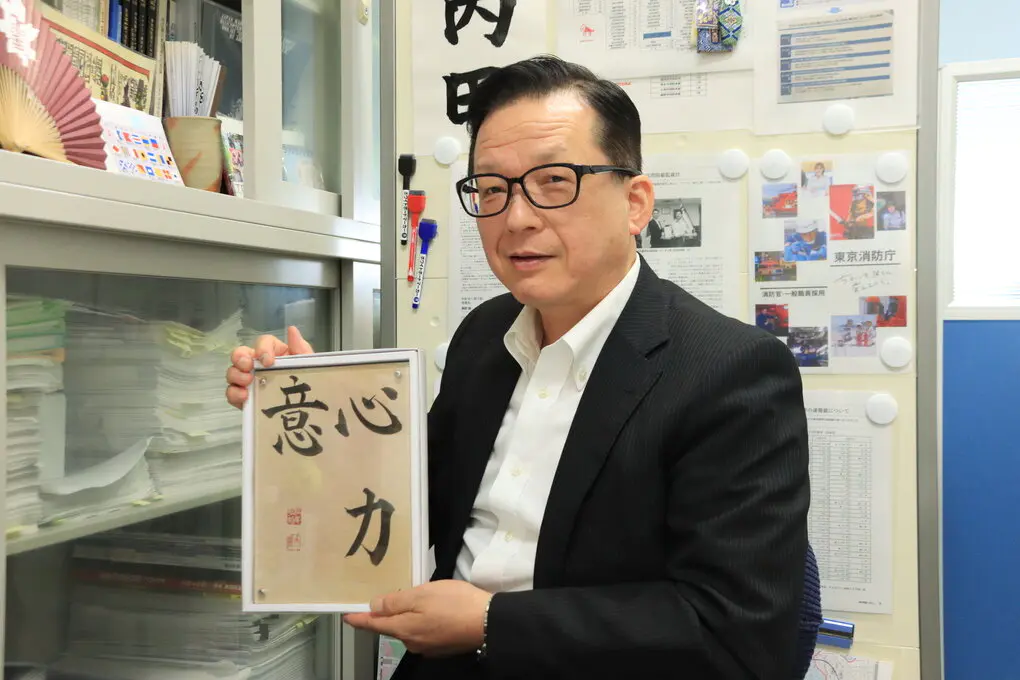 「心、力、意」の色紙を持つ内田准教授