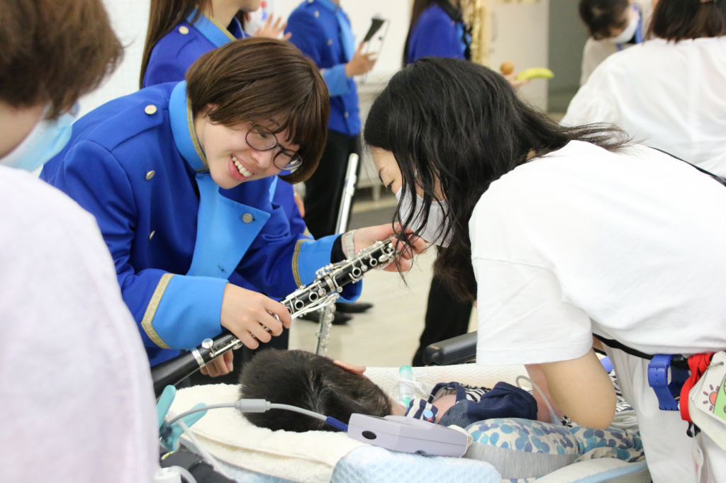 児童のもとに駆け寄り楽器を見せる学生