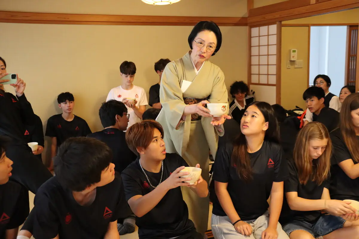 泉水講師に茶碗の持ち方を教わる選手の様子