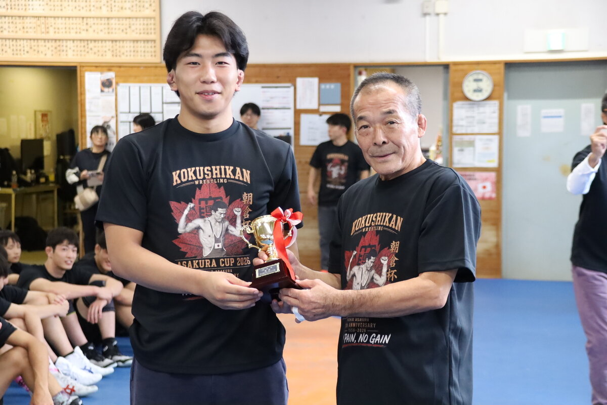 優勝した足利大学付属高等学校の選手にトロフィーを手渡す朝倉教授